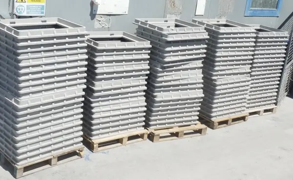 Rows of grey composite underground enclosure bodies stacked on pallets outside the facility.