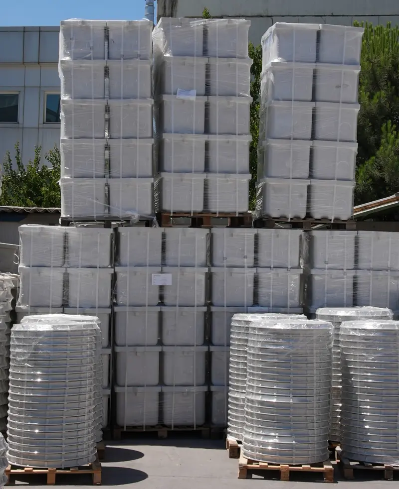 Mixed stock of rectangular enclosures and circular risers on pallets.