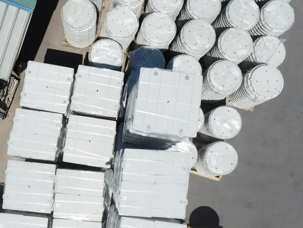 Top-down view of stacked rectangular composite covers alongside circular composite risers.