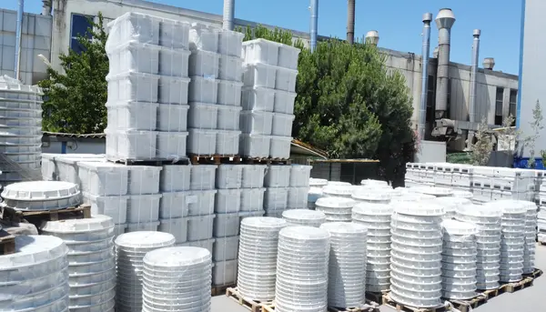 Wrapped composite enclosures palletised in the outdoor stock area beside the facility.
